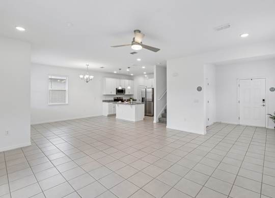 A spacious white room with a ceiling fan and tiled flooring.