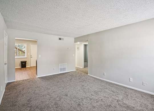 A spacious room with carpeted floor and white walls.