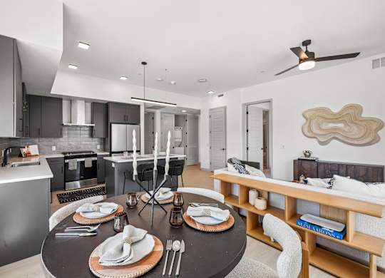 A modern kitchen with a dining table set for two.