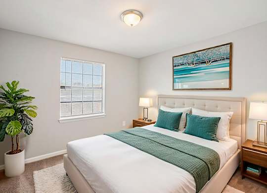 A bedroom with a large bed and a potted plant.