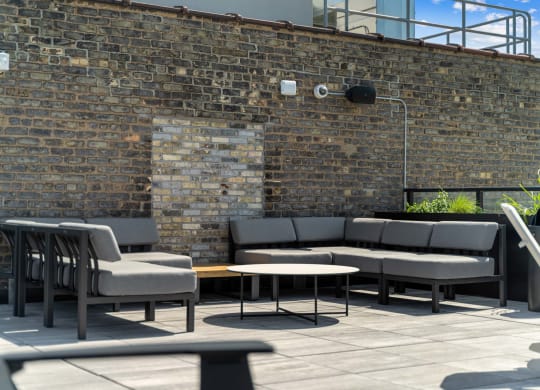 a seating area with couches and tables in front of a brick wall