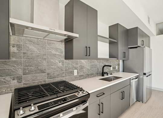 A modern kitchen with a stove, sink, and refrigerator.