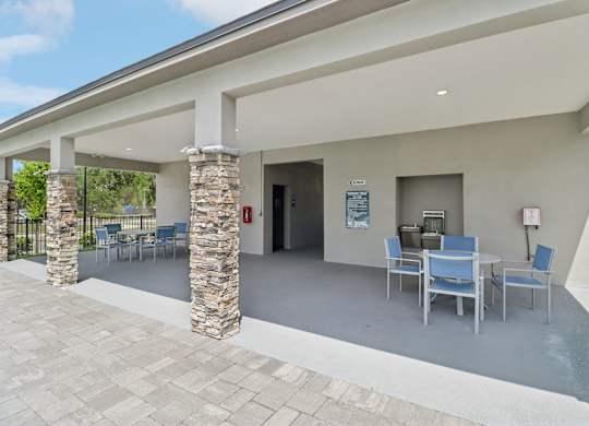 A patio area with a table and chairs under a roof.