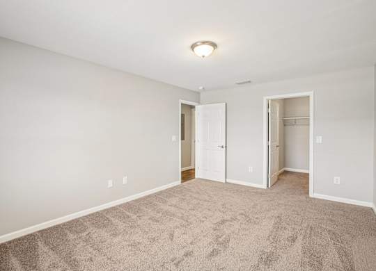 A room with carpeted floor and two open doors.