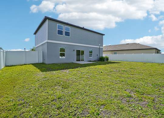 A grey house with a white fence in the front yard.