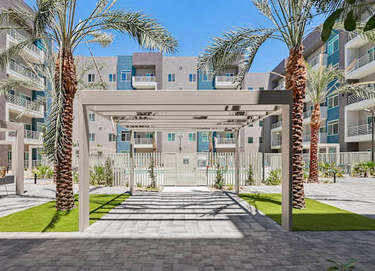 A modern building with a white gate and palm trees in front.