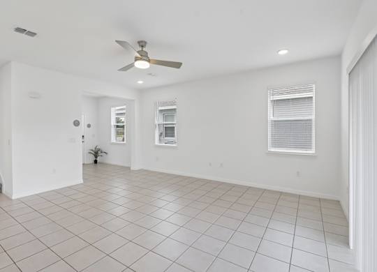 A spacious room with a ceiling fan and tiled flooring.