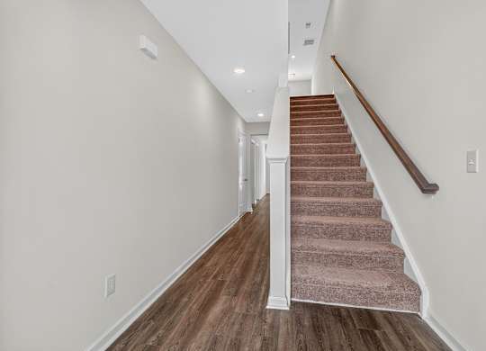 A staircase with a brown carpeted runner and wooden steps.