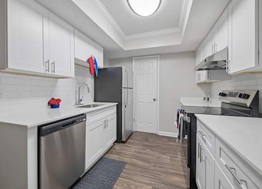 A kitchen with white cabinets and a stainless steel dishwasher.