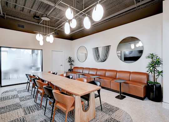 A conference room with a long table, chairs, and mirrors on the wall.