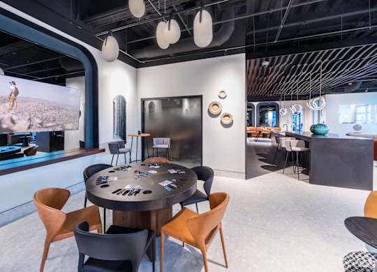 A modern conference room with a large screen and a round table with chairs.