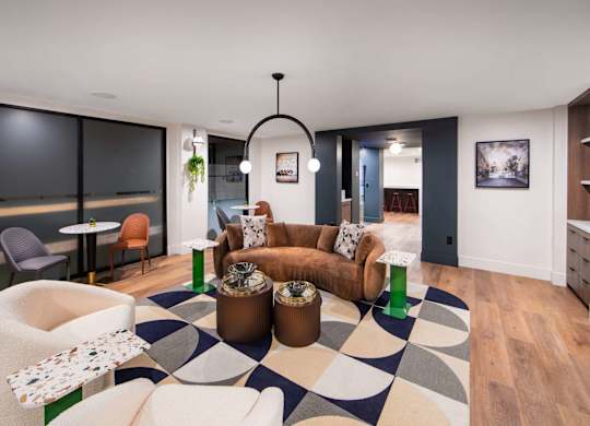 A modern living room with a black and white rug and a variety of seating options.