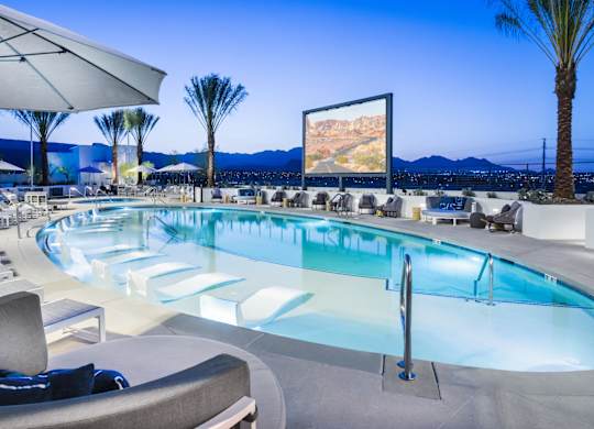 A large screen is mounted on a wall above a swimming pool.