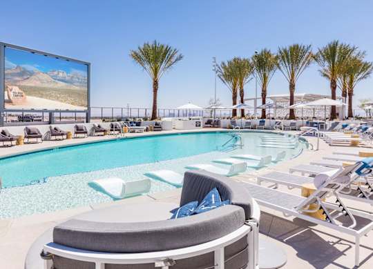 A large screen is mounted on a wall above a pool.