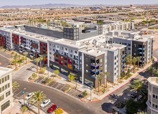 A modern multi-story building with a parking lot in front.