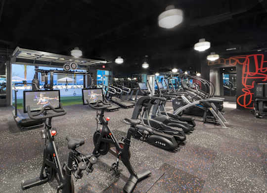 A gym with a row of stationary bikes.