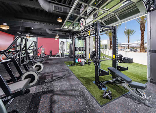 A gym with a red wall and black flooring.