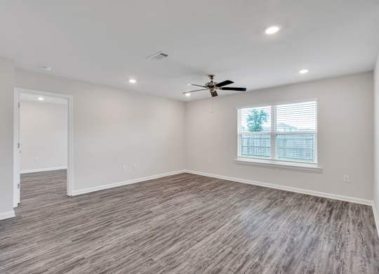 A room with a ceiling fan and a window with blinds.