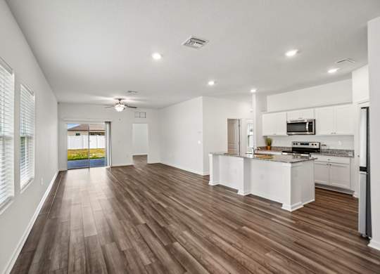 A spacious kitchen with white cabinets and a wooden floor.