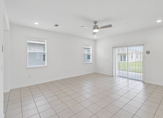 A spacious room with a ceiling fan and tiled flooring.