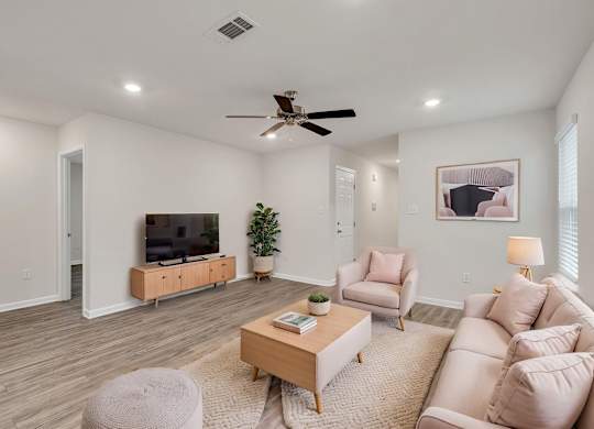 A living room with a ceiling fan and a flat screen TV.