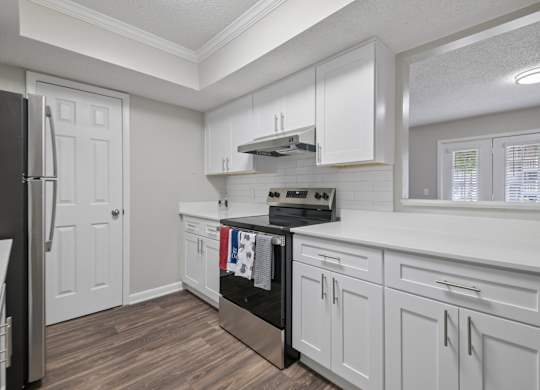 A kitchen with white cabinets and a black stove top oven.
