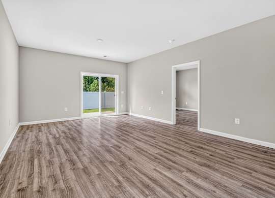 A room with wooden flooring and a sliding glass door.