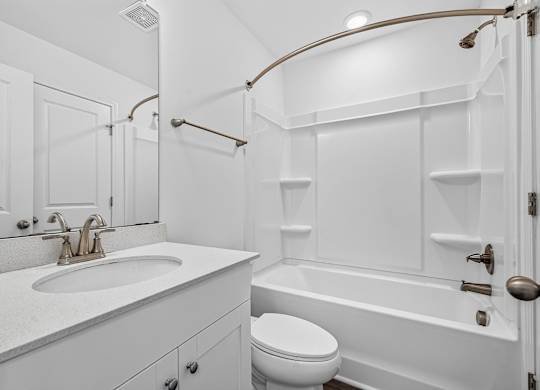 A white bathroom with a toilet, sink, and bathtub.