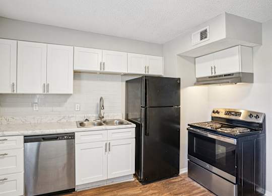 A kitchen with black appliances and white cabinets.