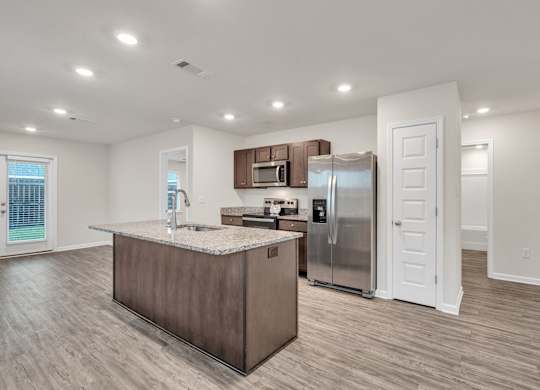 A kitchen with a refrigerator, microwave, and sink.