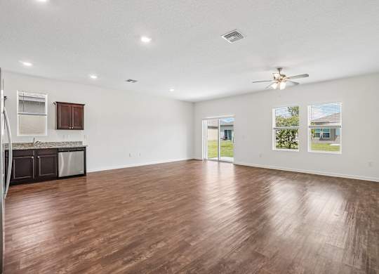 A spacious room with wooden flooring and a ceiling fan.