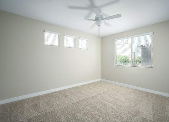 A room with a ceiling fan and carpeted floor.