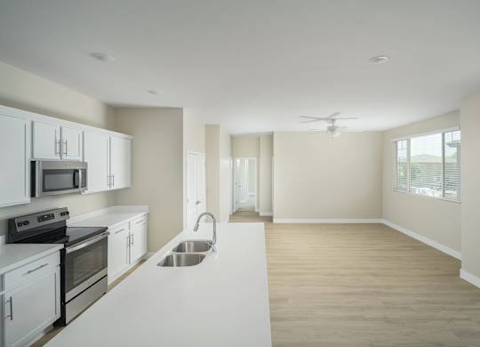 A kitchen with white cabinets and a stainless steel sink.