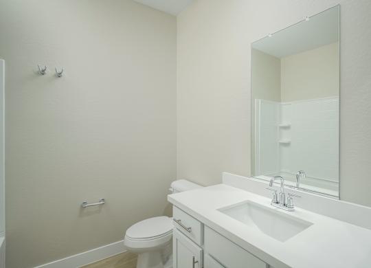 A white bathroom with a toilet, sink, and mirror.