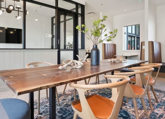a dining room with a long wooden table and orange chairs