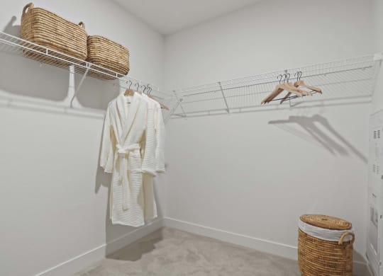 a walk in closet with a white robe and shoe rack