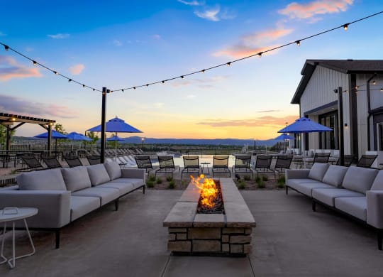 a patio with couches and chairs and a fire pit at dusk