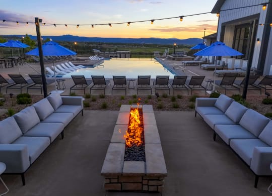 a lounge area with couches and chairs around a fire pit