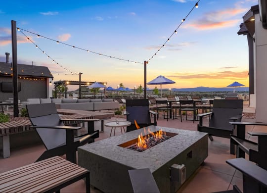 a fire pit on the patio of a restaurant with tables and chairs