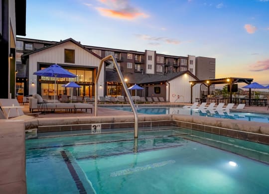 a swimming pool with chairs and umbrellas at dusk