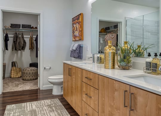 Apartments In South Scottsdale For Rent - Lucent Scottsdale - Bathroom With Wood-Vinyl Plank Flooring, A Large Vanity Mirror, Quartz Countertops, Ceramic Tile Backsplashes, Dual Sinks, Toilet, Large C