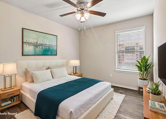 A bedroom with a bed, a ceiling fan, and a painting on the wall.