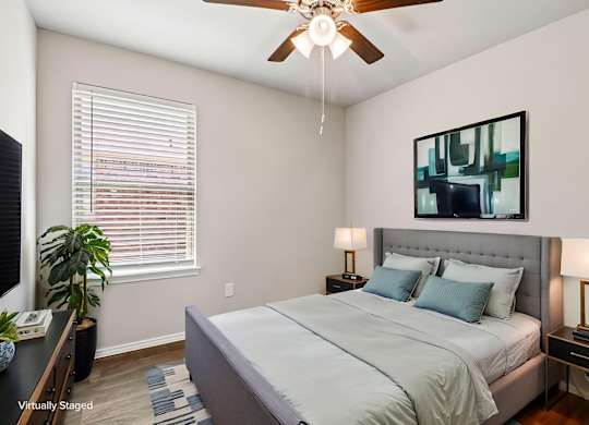 A bedroom with a bed, nightstands, and a ceiling fan.