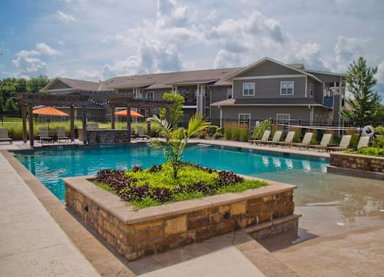 A large swimming pool surrounded by a stone planter with plants in it.