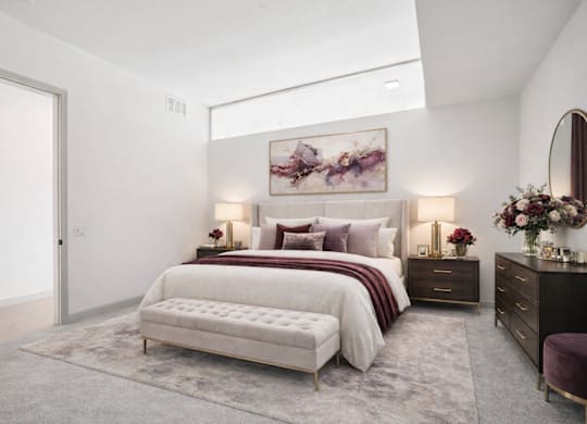 A bedroom with a large bed, a bench, and a painting on the wall.