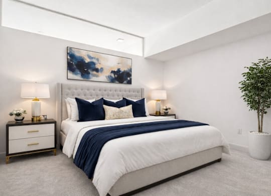 A bedroom with a large bed and a potted plant.