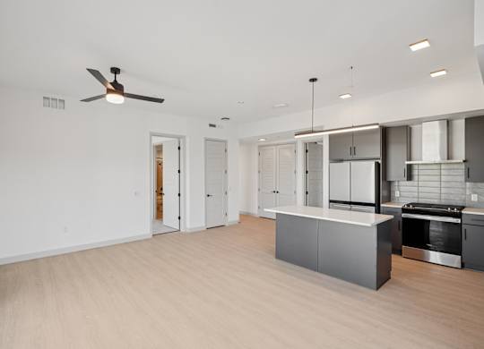 A spacious kitchen with a ceiling fan and modern appliances.
