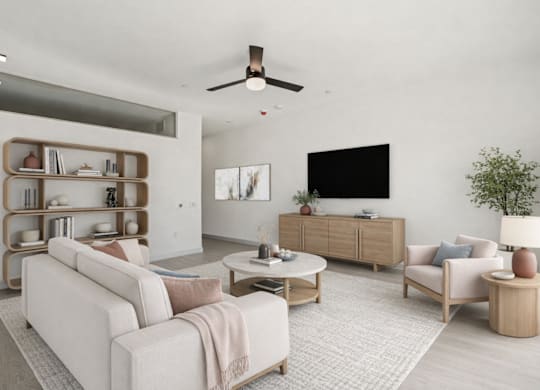 A living room with a white couch, a wooden coffee table, and a TV on the wall.