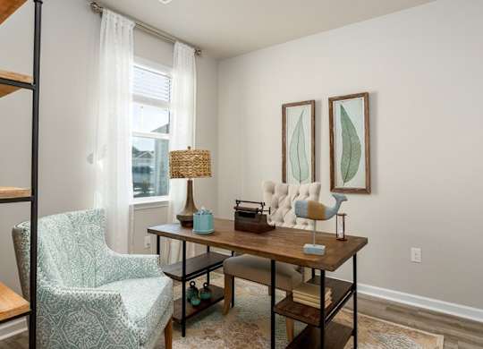 a home office with two paintings on the wall and a wooden desk with a chair and a