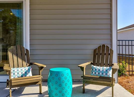 Houses for Rent in Myrtle Beach, SC - The Palmer at Carolina Forest - Spacious Private Patio With a Fenced Yard, Two Wooden Armchairs, and a Blue Side Table
